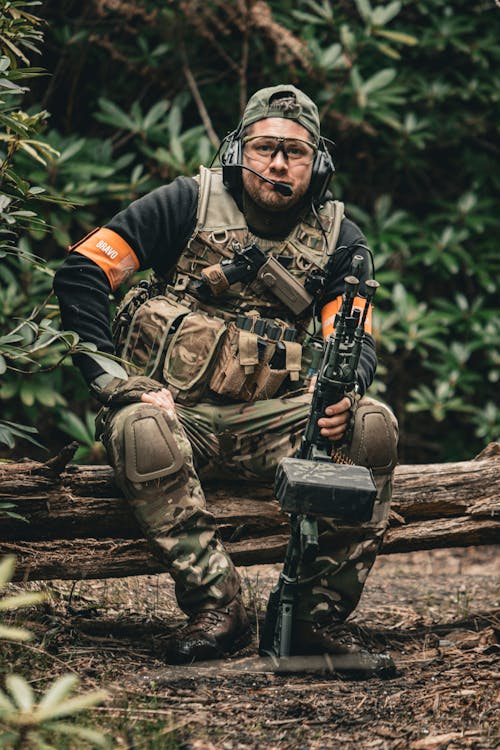 Soldier with Machine Gun Sitting on Tree Trunk