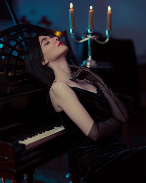 Model in a Black Suede Evening Dress and Chiffon Gloves Leaning Against a Piano