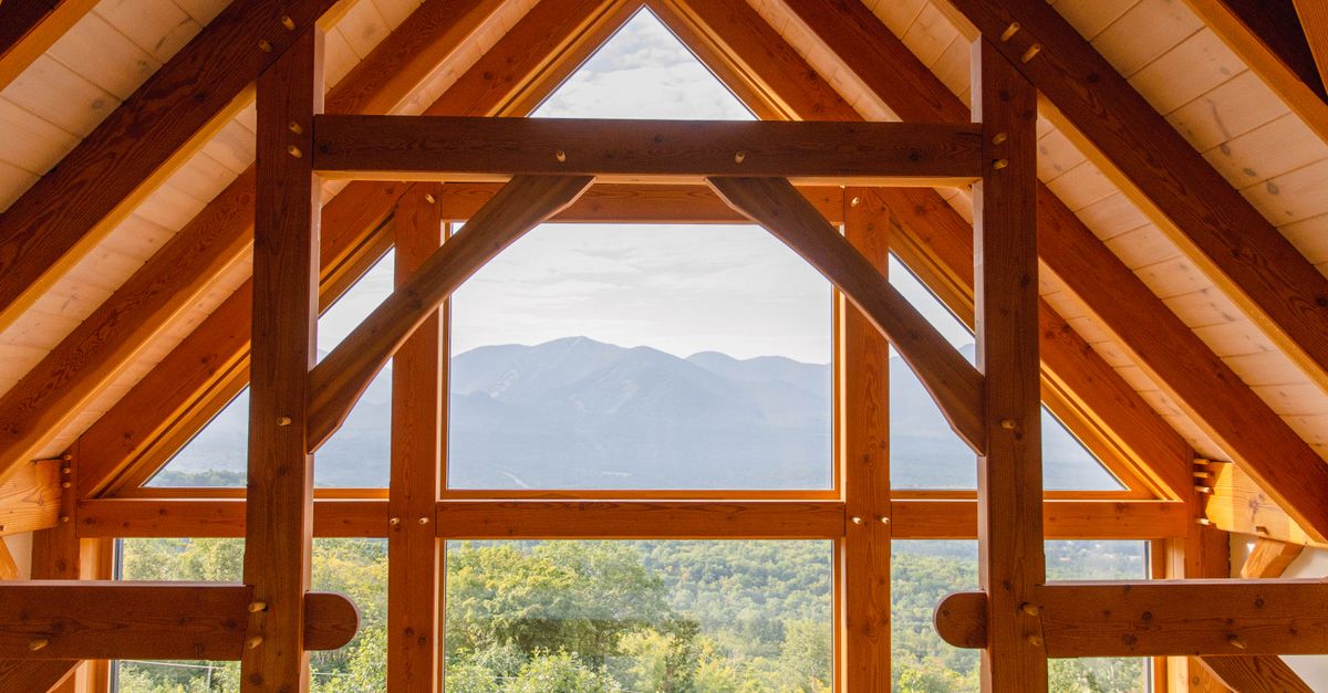 A rustic wooden interior featuring large windows framing a scenic mountain view.