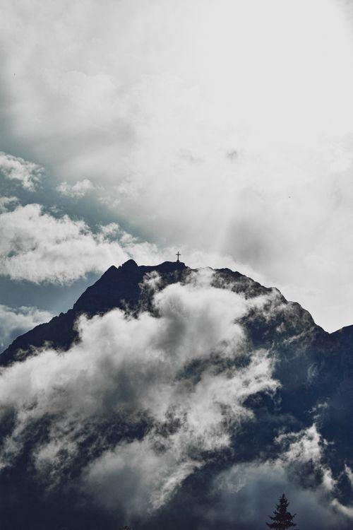 Free A striking mountain peak enveloped by dramatic clouds under an overcast sky. Stock Photo