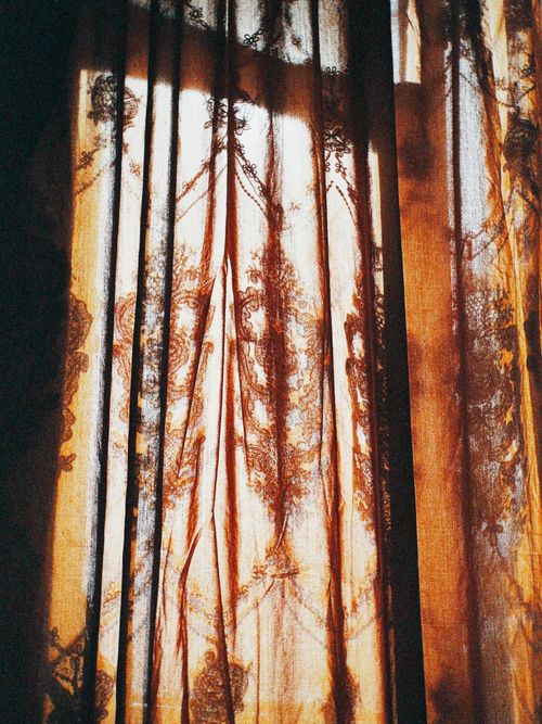 Free Ornate embroidered curtain with light creating a warm, artistic pattern. Stock Photo