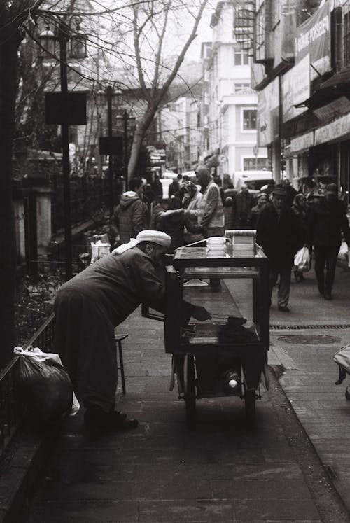 Black and White Photo of a Vendor and People Walking Down the Street