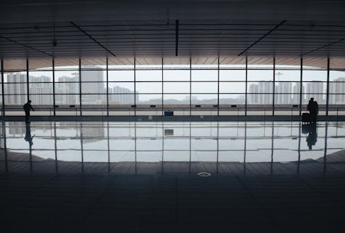 People Standing by a Large Window at the Airport 