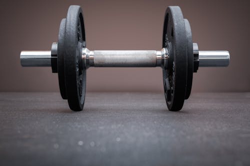 A dumbbell bar loaded with weight plates on the floor at the gym. Bodybuilding equipment on a clean background with empty space for text. Fitness, weight training or healthy lifestyle conc...
