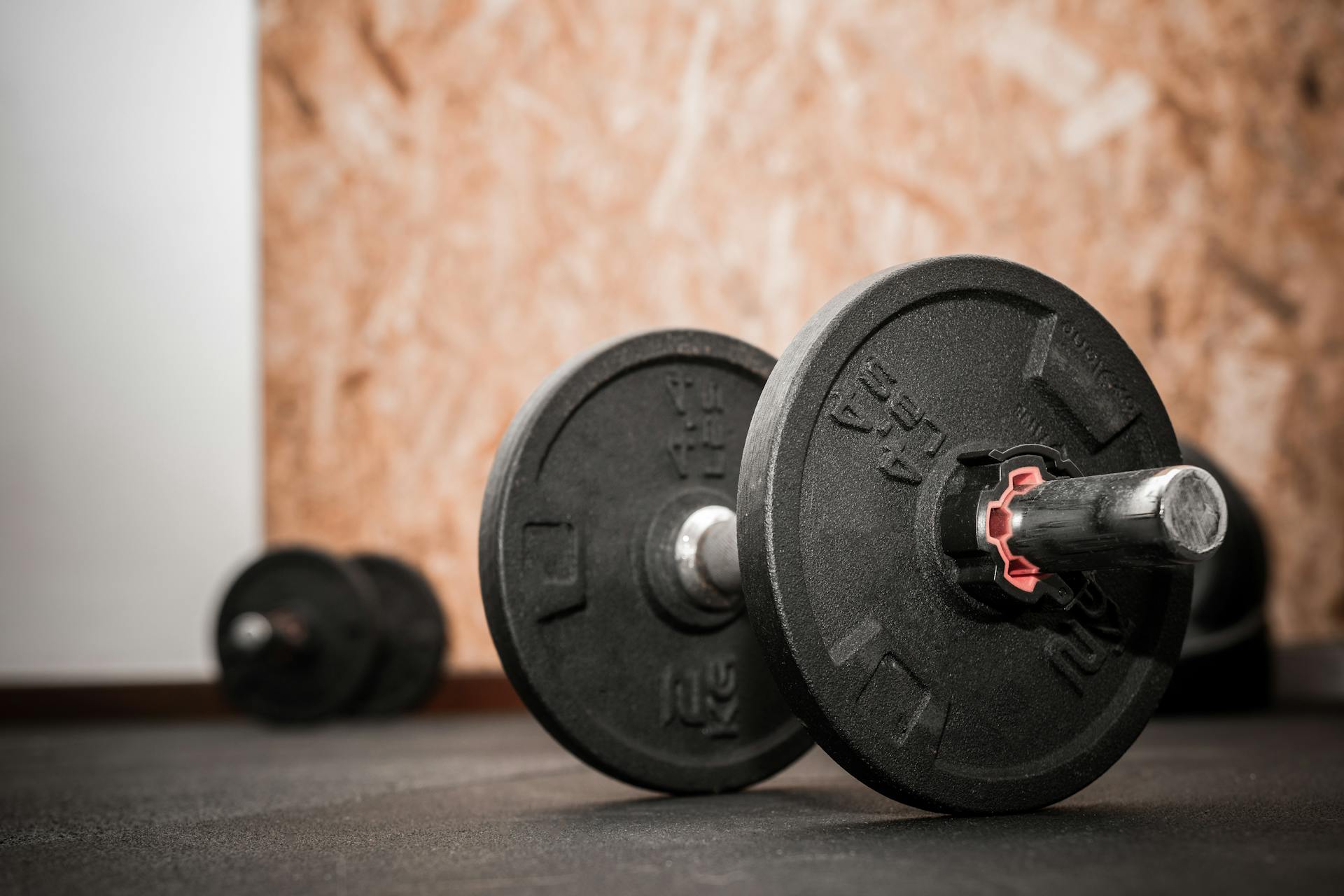 Close-up of 4.4lbs or 2Kg loadable dumbbell. Bodybuilding equipment on the floor at the gym with blurred background and empty space for text. Fitness, weight training or healthy lifestyle ...