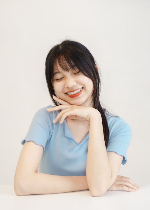 A Young Woman Smiling and Touching her Face