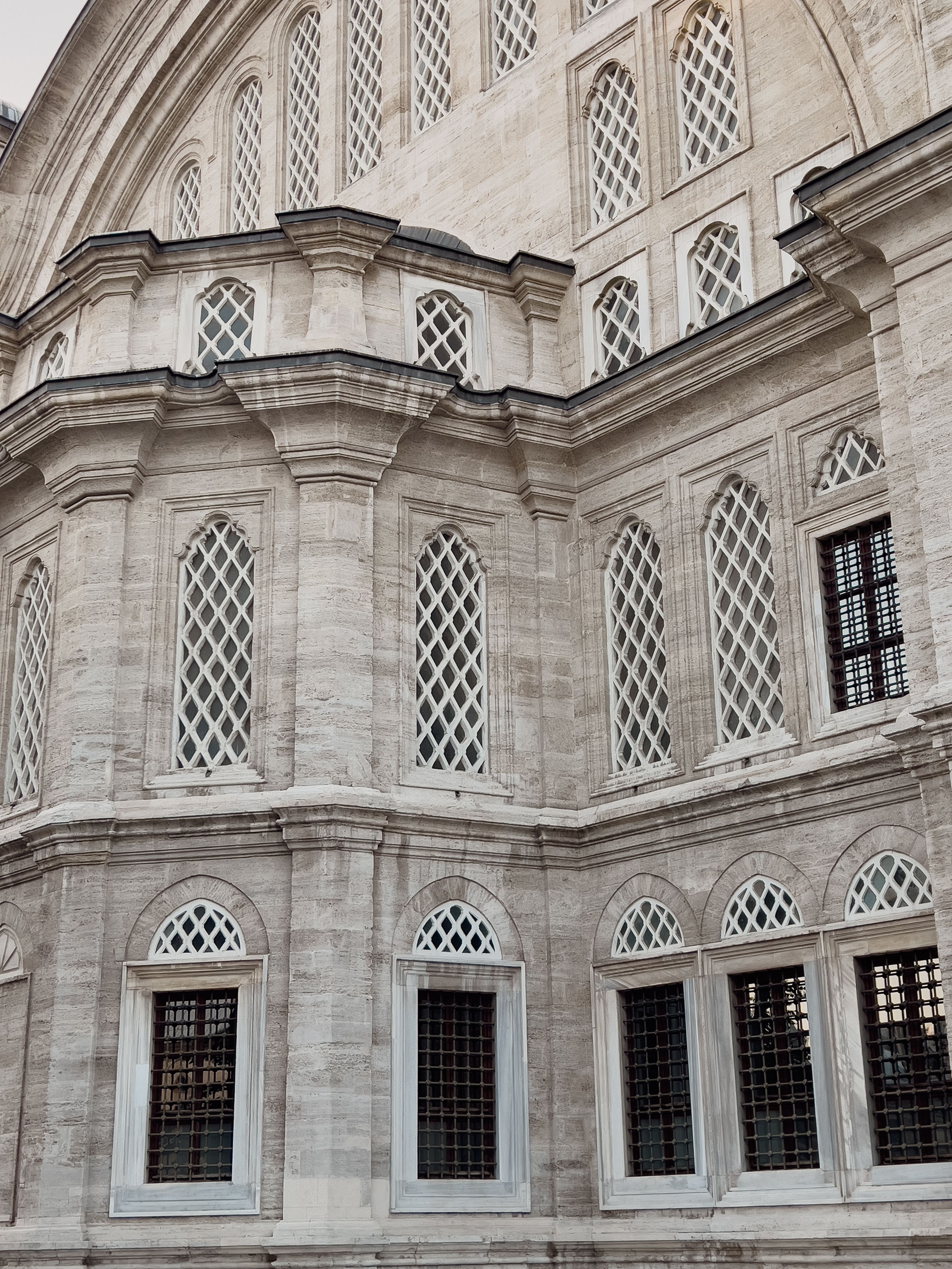 Detailed view of the Nuruosmaniye Mosque's Ottoman facade in Istanbul, showcasing intricate windows and stonework.