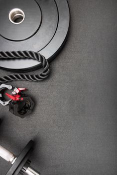 A composition of gym equipment including weights, rope, and clamps on a dark background. Perfect for fitness themes.