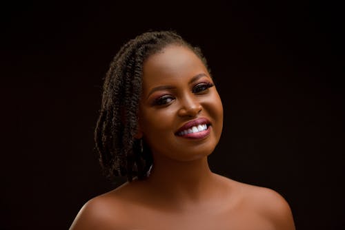 Portrait of a Smiling Woman with Dreadlocks Posing against Black Background