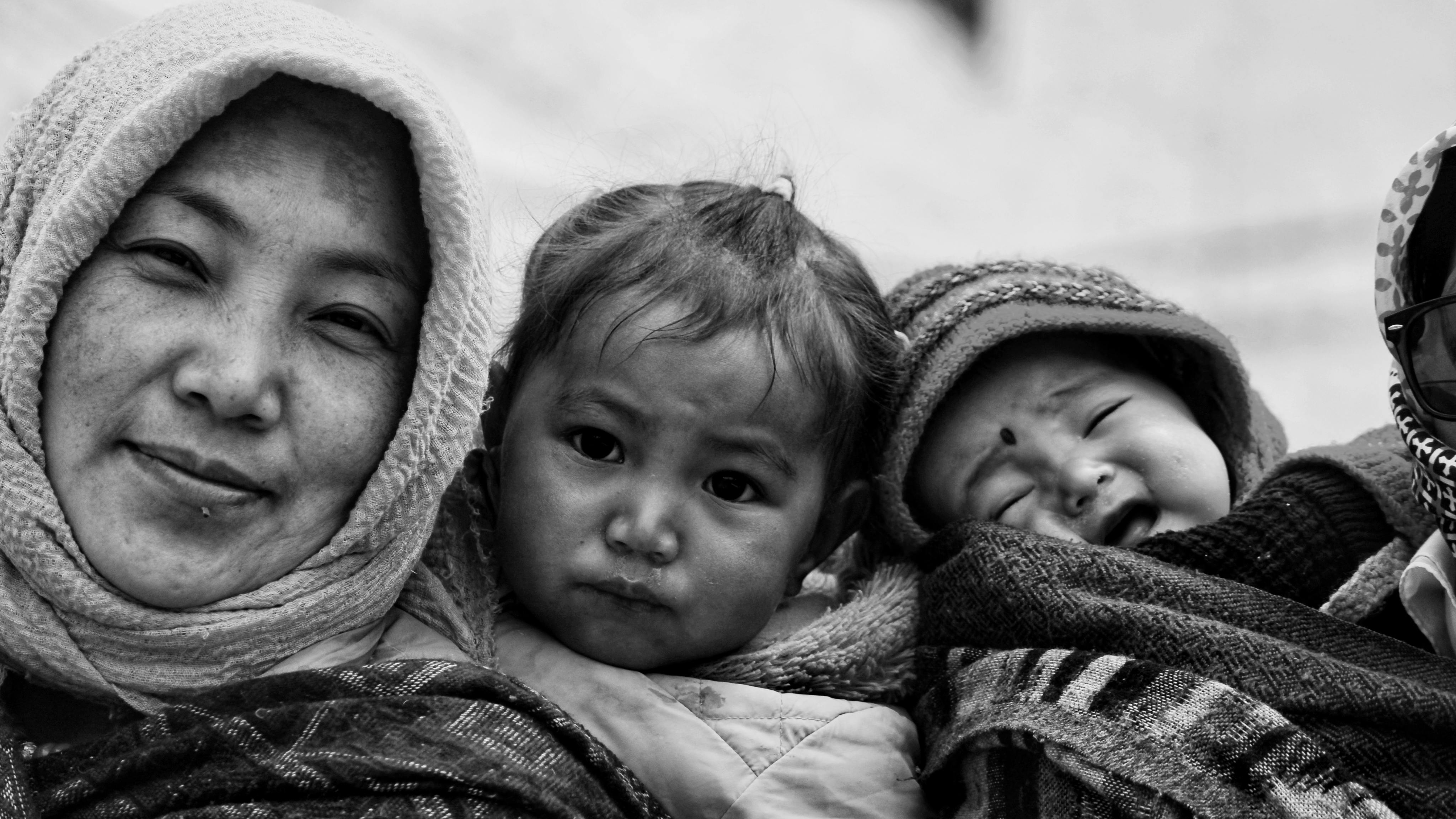 Intimate black and white family portrait capturing a mother with her children in traditional attire.
