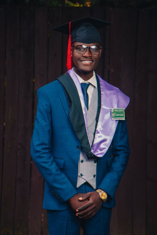 Free Proud young man in graduation attire smiles for the camera, celebrating his academic achievement. Stock Photo