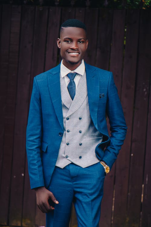 Young Elegant Man in a Suit Standing near a Wooden Fence 