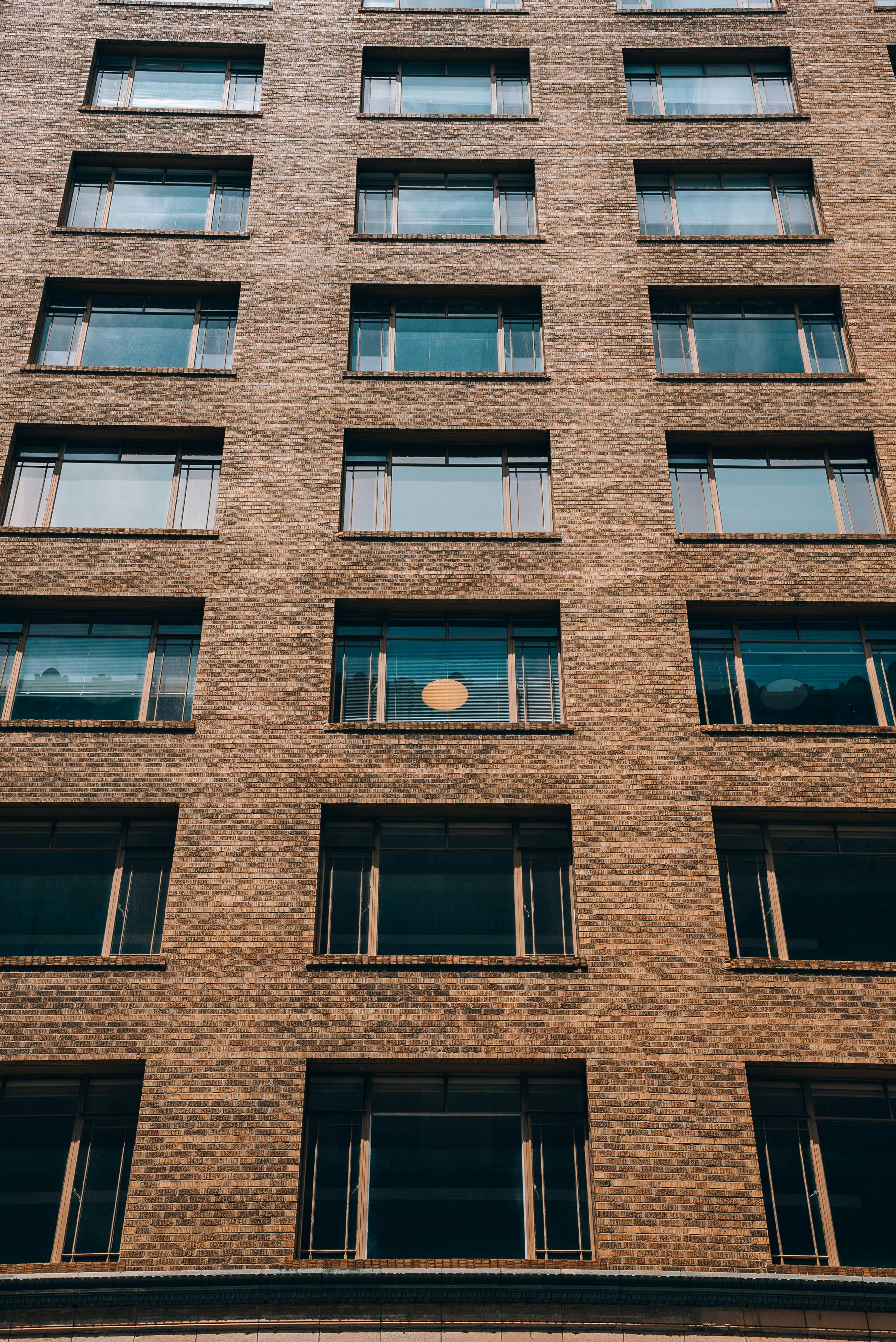 Low angle view of a brick residential building facade, highlighting its symmetry and urban aesthetics.