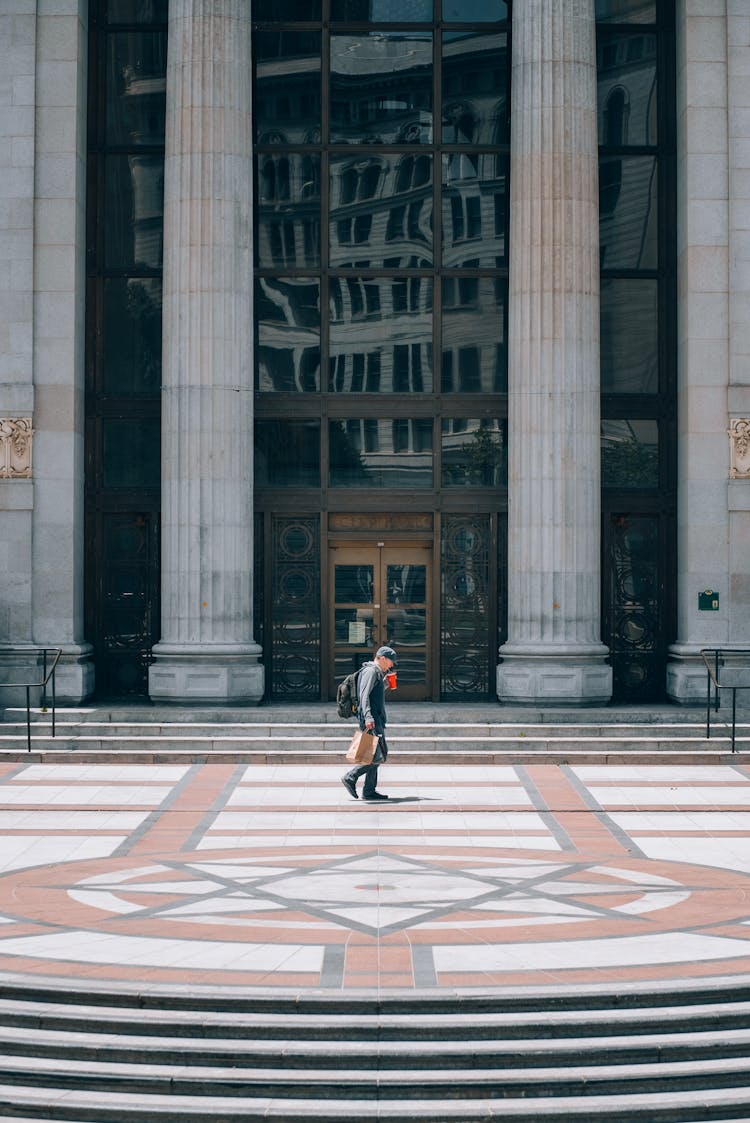 Person Walking Near Building Columns