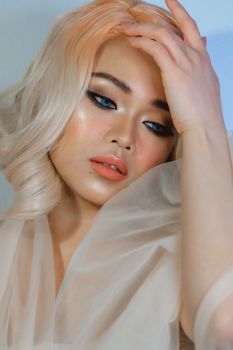 Close-up portrait of a young woman with elegant makeup and hairstyle posing in a studio.