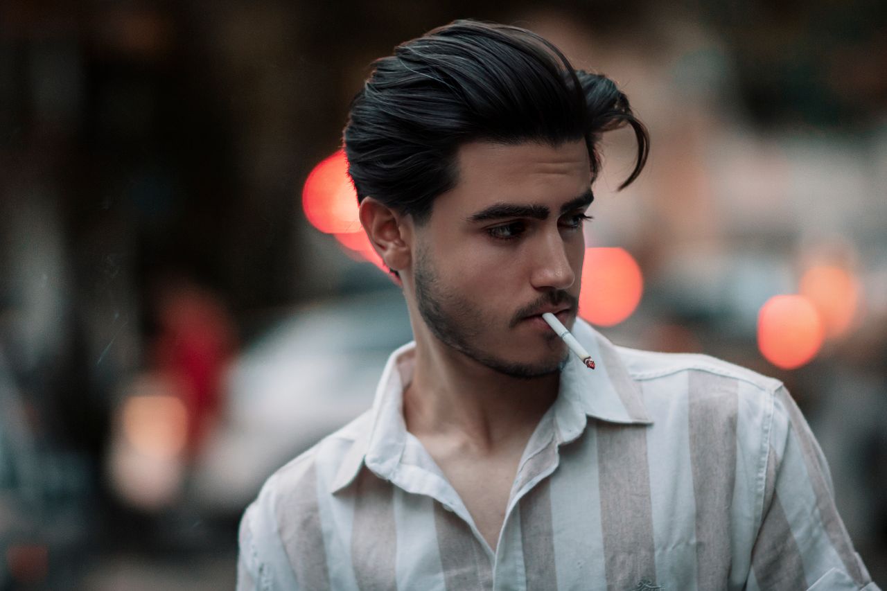portrait of a stylish young man smoking with an urban tehran backdrop