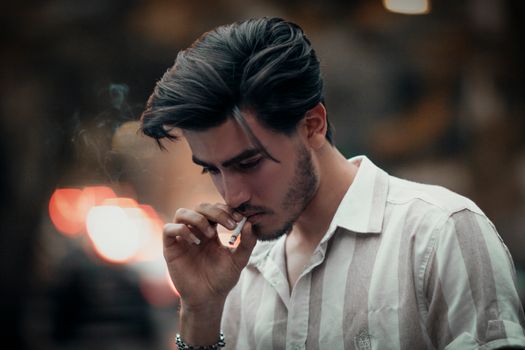A contemplative young man smoking, captured in a moody outdoor setting in Tehran.