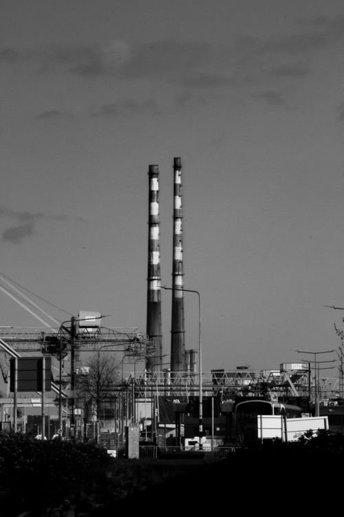Free Black and white photo of twin chimneys in urban industrial area, emphasizing air pollution. Stock Photo