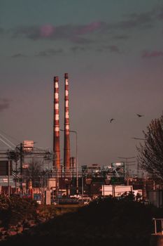 Urban scene featuring twin smokestacks emitting minimal pollution under twilight skies.