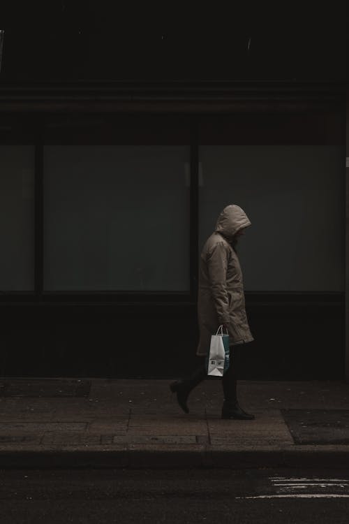 Dark Photo of a Person Walking on the Sidewalk