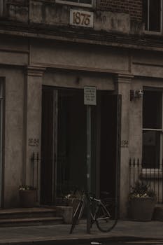 Dark, vintage city street view with a bicycle and historic building entrance.