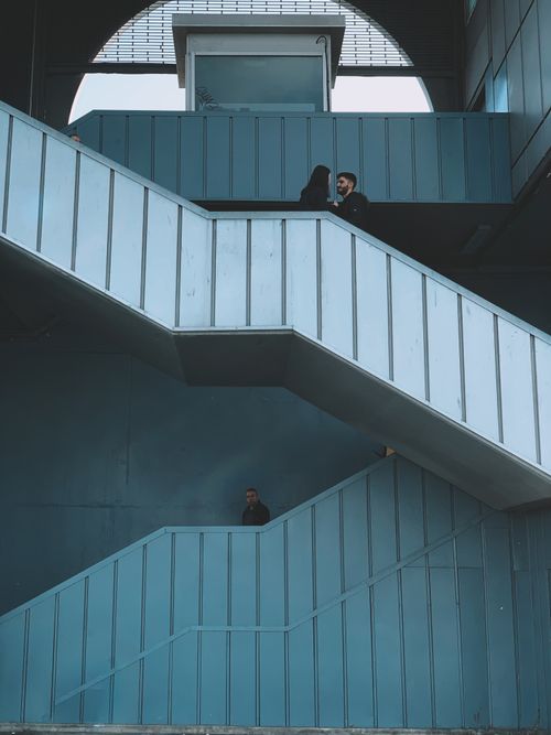 Free Vertical shot of blue metal staircase indoors with people walking, showcasing modern architecture. Stock Photo