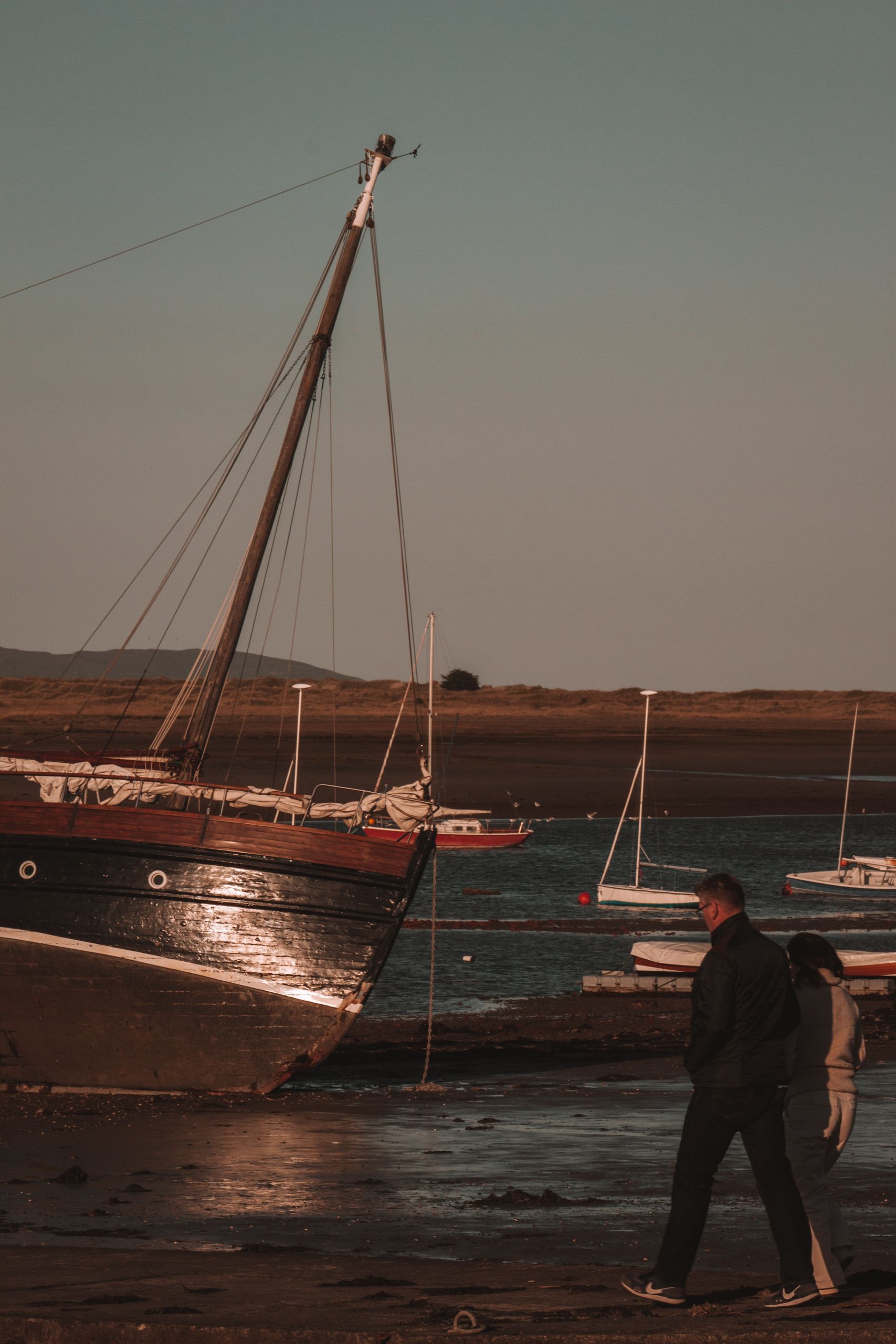 Couple Walking on a Beach With Boats Stranded after Low Tide · Free ...