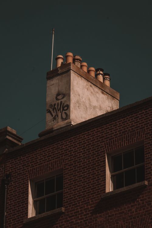 Free Low angle shot of a brick building chimney with graffiti. Stock Photo