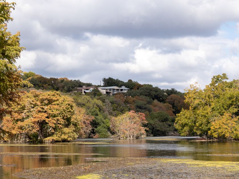 A house among autumn trees beside a lake in New Braunfels, Texas
