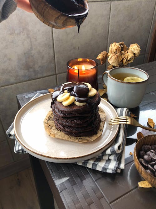 Free Chocolate Pancakes with Banana and Chocolate and a Cup of Coffee on the Table  Stock Photo