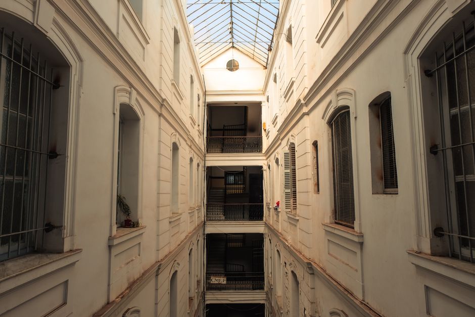Explora la belleza arquitectónica del patio de un edificio histórico con tragaluz de cristal y fachada blanca.