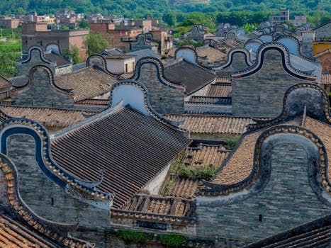 Aerial view of ancient Chinese village rooftops with distinct curved designs.