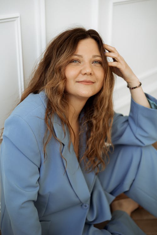 Smiling Woman Posing in Blue Suit Holding Fingers on Temple