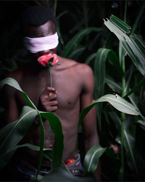 Shirtless Man with Covered Eyes by Scarf among Plants
