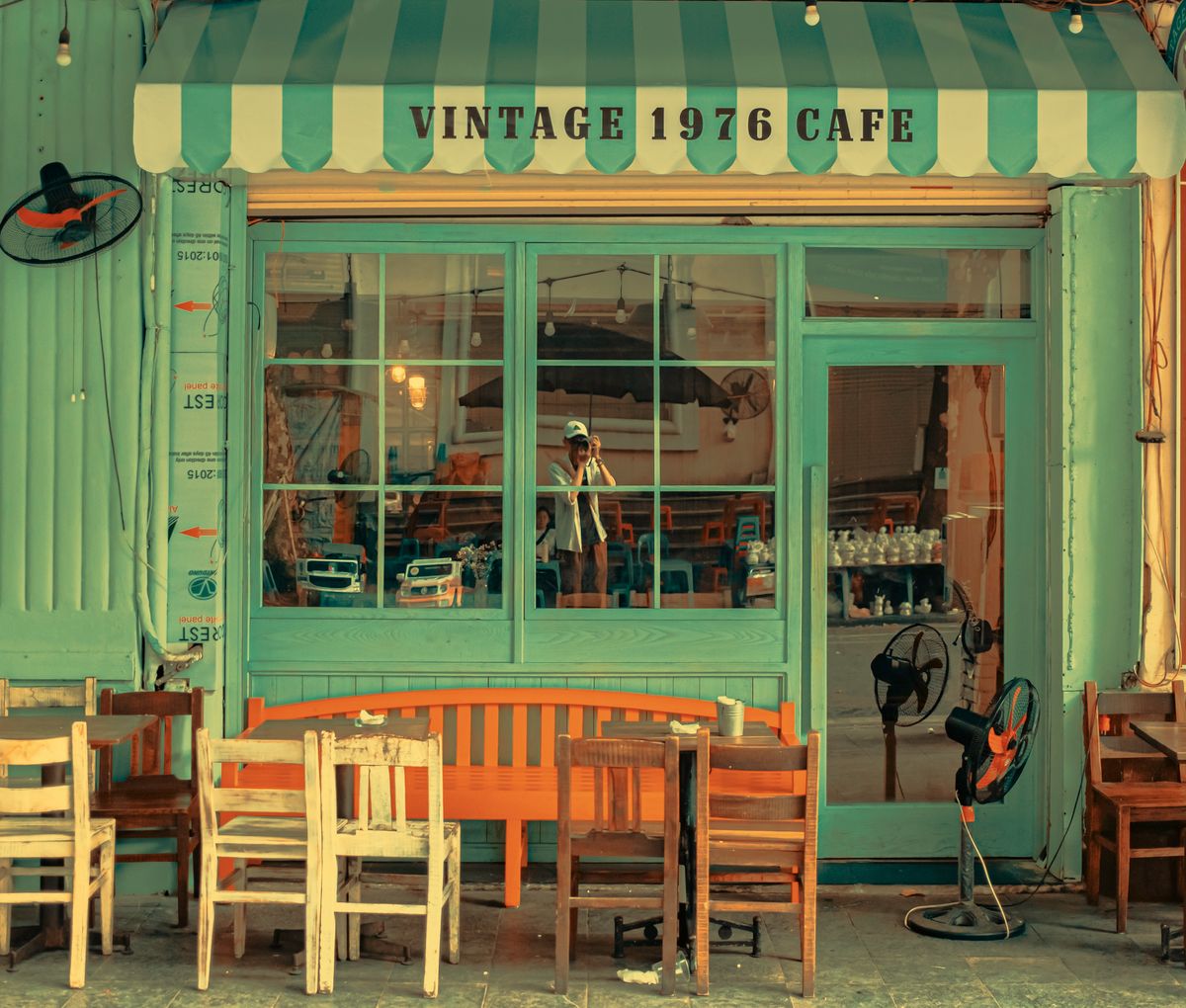 A charming vintage cafe exterior with a turquoise door and striped awning