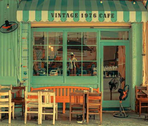 Free Charming vintage café facade featuring retro chairs and tables in a cozy outdoor setting. Stock Photo
