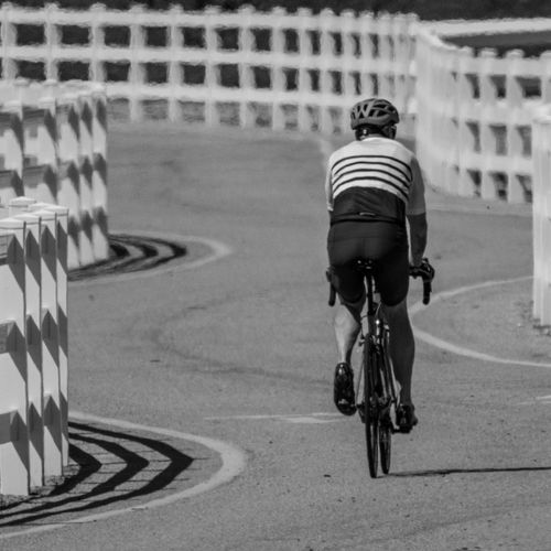 Free A cyclist gracefully navigates a winding road, highlighting the sport of cycling. Stock Photo