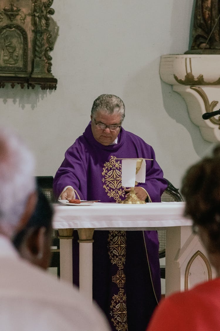 Catholic Priest In Purple Cope With Golden Embroidery Standing At A Podium In A Church