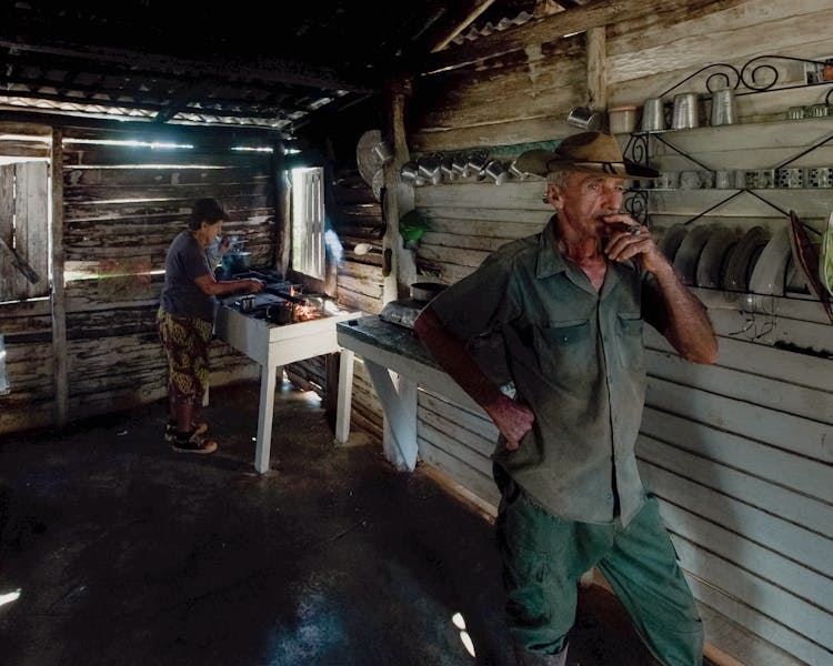 A Woman Cooking And A Man Smoking A Cigar 