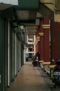 A serene urban alley with closed stores and parked motor scooters, showcasing typical city life in the Philippines. - Fotografer Sidoarjo