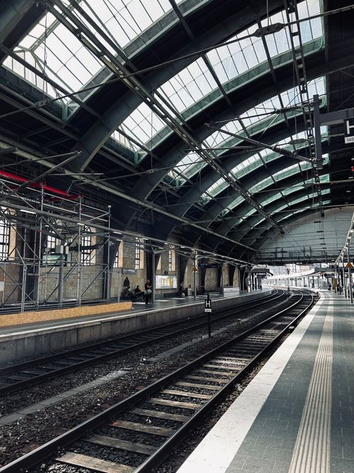 Free Spacious railway station platform showcasing modern architectural elements and empty tracks. Stock Photo