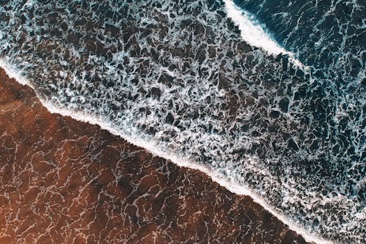 Stunning aerial photograph of ocean waves meeting the sandy shore in Terengganu, Malaysia.