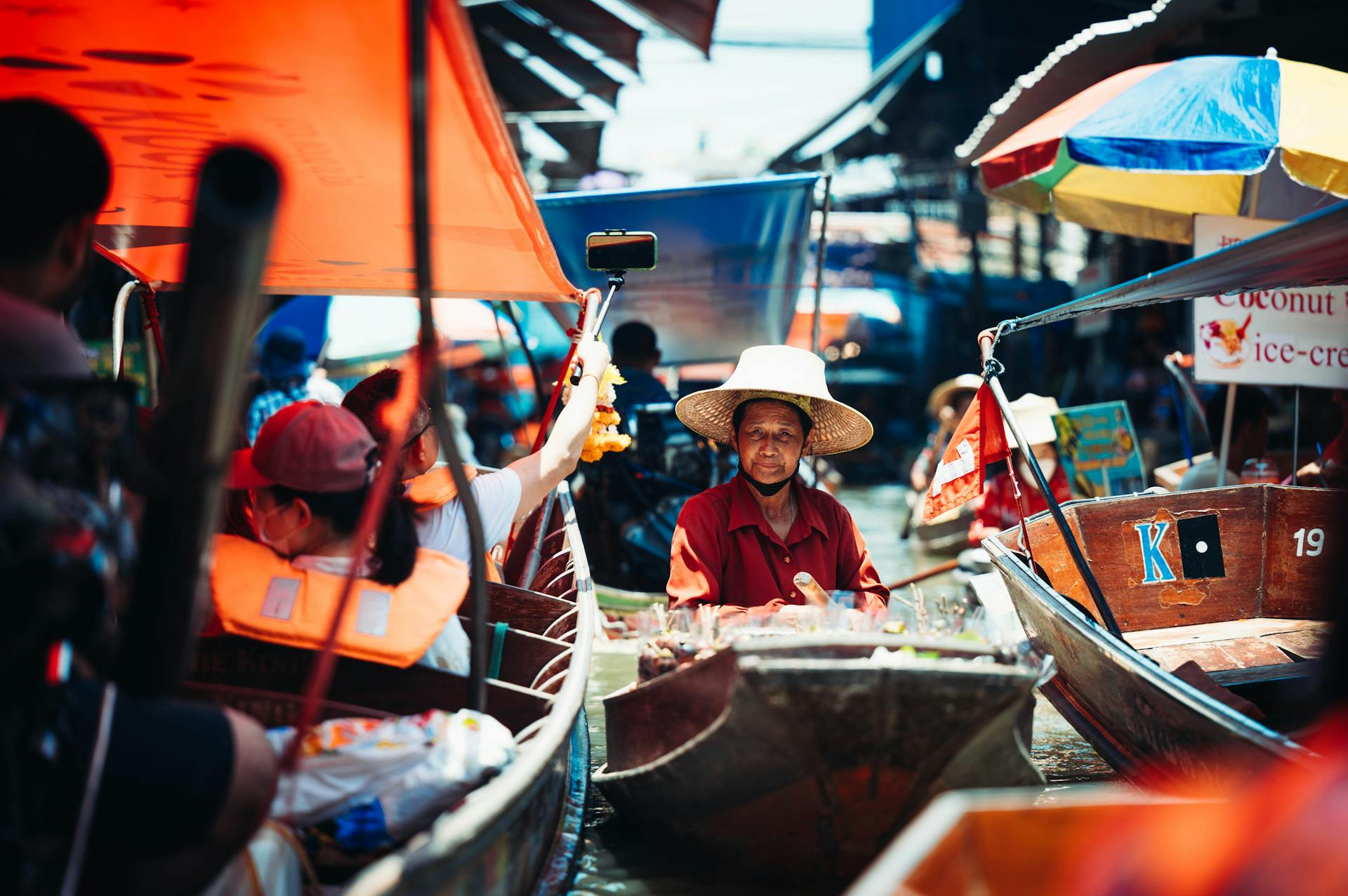 Vibrant market scene at an Asian floating market with people in boats trading goods.