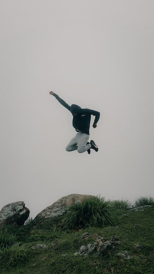 Man in Hoodie Jumping with Arm Raised