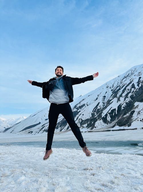 Happy Man Jumping Against Snowy Mountain
