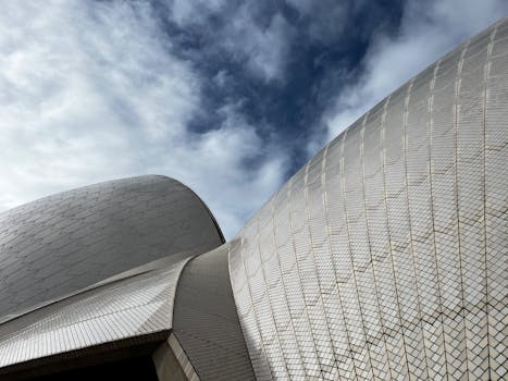 Detailed architectural view of the Sydney Opera House roof against a cloudy sky.
