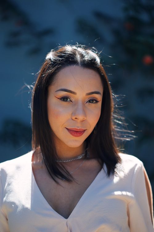 Free Close-up portrait of a young woman outdoors with sunlit background. Vibrant and stylish. Stock Photo