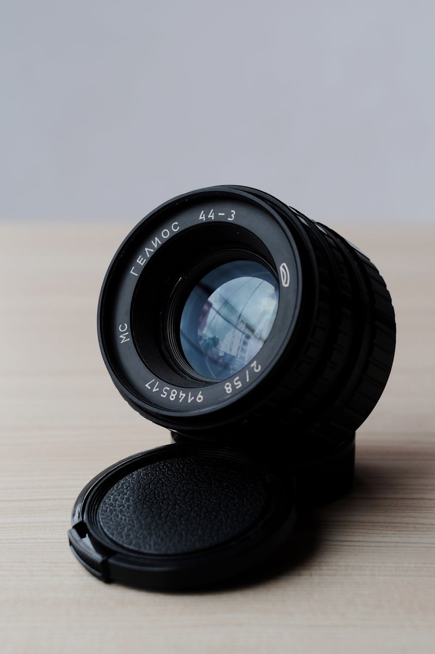 Detailed image of a vintage camera lens with cap on wooden table.