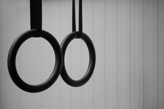 Close-up of black gymnastic rings against a light background, ideal for fitness and exercise concepts.
