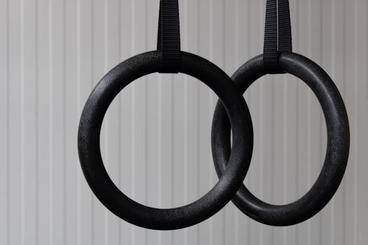 Pair of black gym rings hanging indoors, emphasizing fitness and stability.